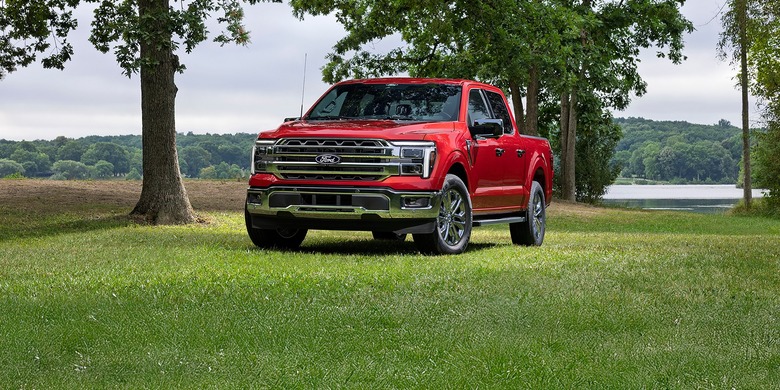 2027 Ford F-150 red truck grass trees