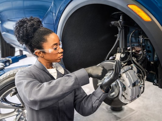 certified GM service technician performing brake repair on a vehicle in a repair shop in tempe, AZ