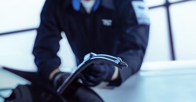 Cadillac certified mechanic replacing the windshield wipers in a repair shop near Gilbert, AZ