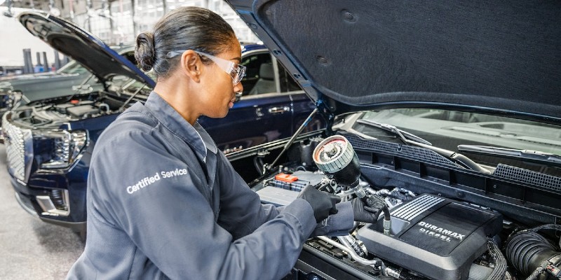 certified GM service technician filling a vehicle's oil at a repair shop in Tempe, AZ