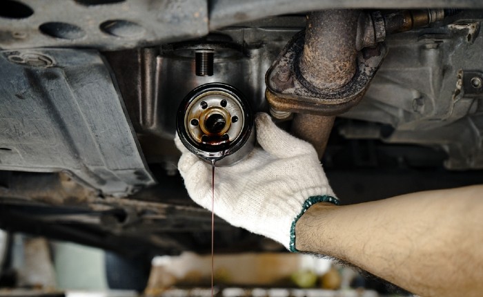 Hand with a white glove removing a car oil filter