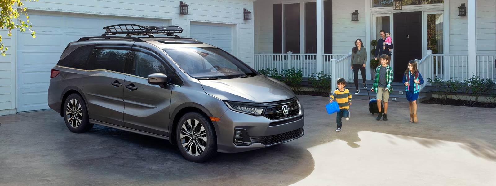 2027 Honda Odyssey parked in front of a modern home, exterior front three-quarter view