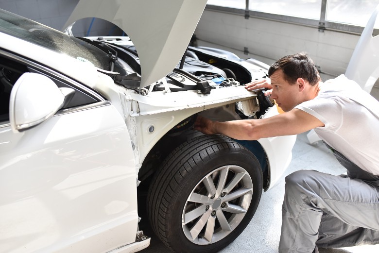 Certified technician inspecting collision repair bodywork at Olson Chevrolet