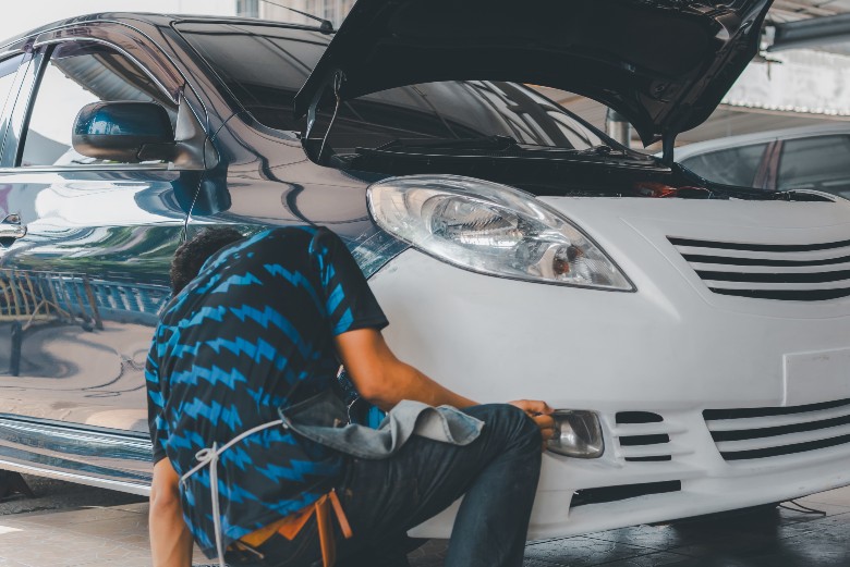 Technician installing a replacement bumper part at Olson Chevrolet