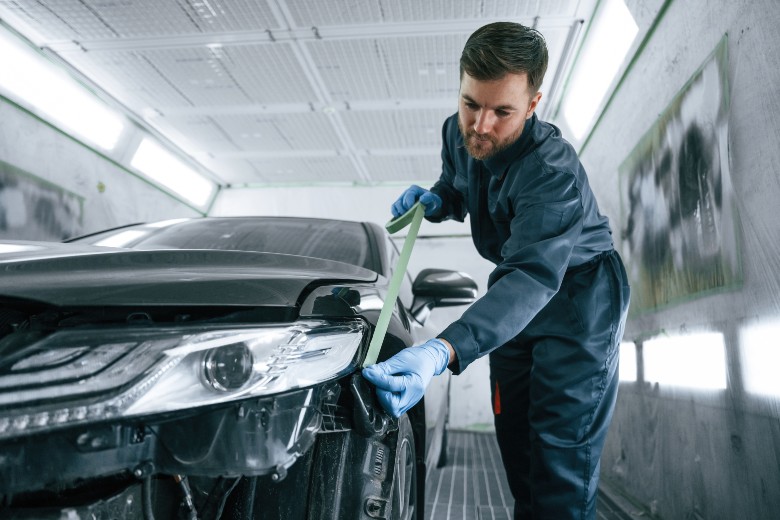 Technician carefully prepping sensor area near headlight before recalibration at Olson Chevrolet
