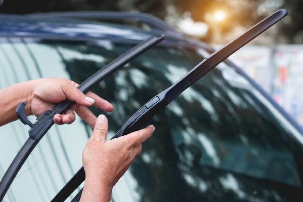 two hands holding two wiper blades