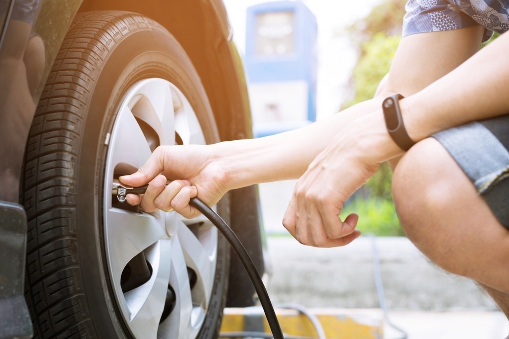 person filling a car tire with air
