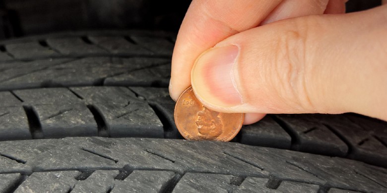 person testing the tire depth with a penny