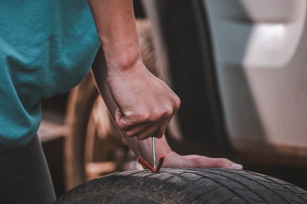 Woman fixing her tire with a tire plug Woman fixing her tire with a tire plug