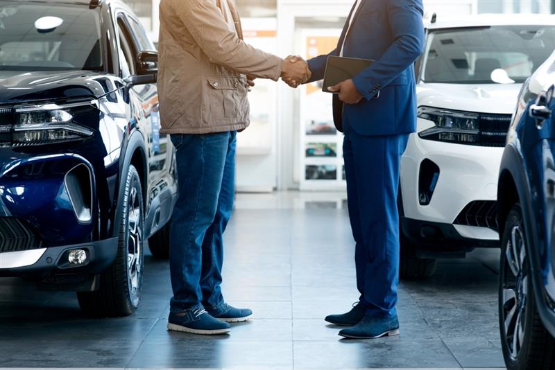 two men shaking hands in a dealership