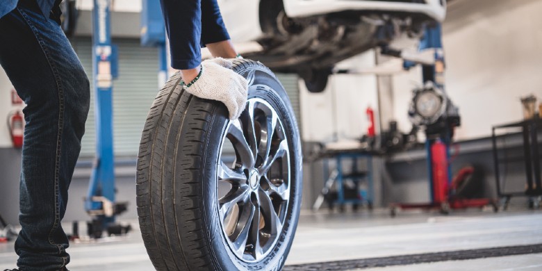 Technician rolling a car tire on a service center floor